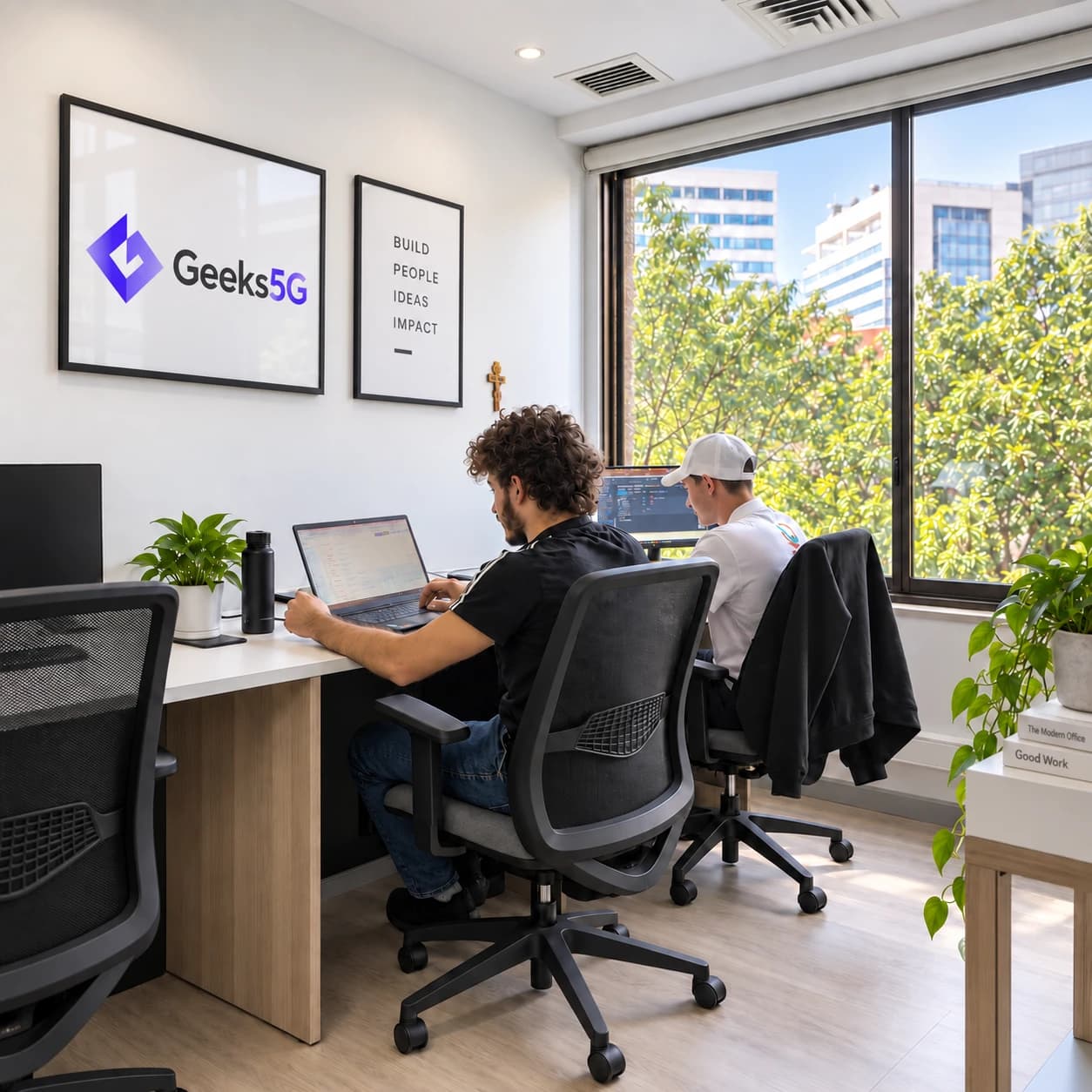 Two Geeks5G Studios teammates working together at a desk in the Geeks5G office